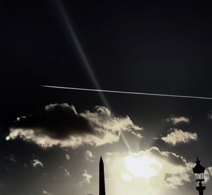 Low angle view of sun shining through clouds