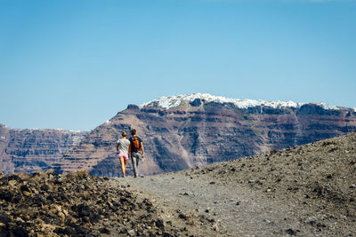 Rear view of man and woman walking against mountain