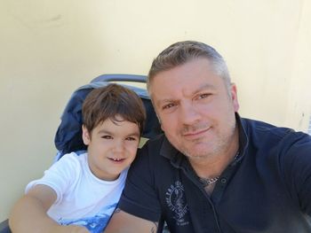 Portrait of father and son against wall