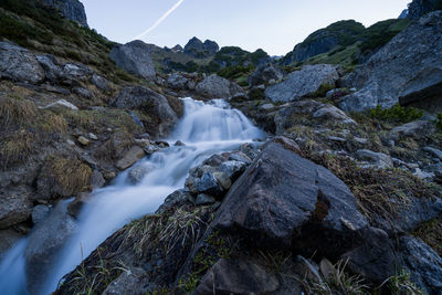 Scenic view of waterfall amidst rocks against sky