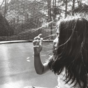 Rear view of girl holding plants against trees