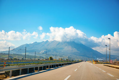 Road by mountains against blue sky