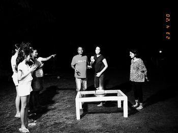 Group of people standing against wall at night