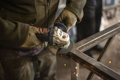 Midsection of man using grinder in factory