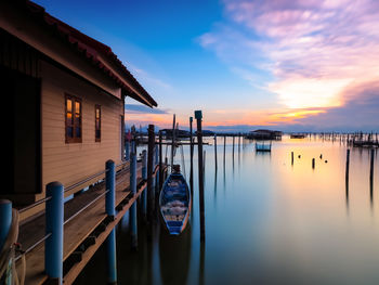 Wooden posts on building against sky during sunset