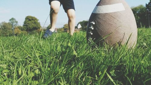 Low section of person playing with rugby ball on grassy field