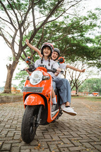 Portrait of young woman riding motor scooter on road