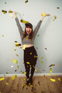 Full length portrait of young woman standing against wall