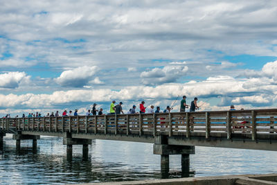 People by sea against sky