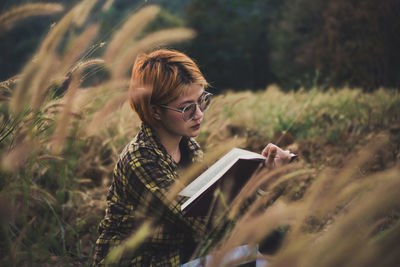 Young woman sitting reading a book at nature in the evening.