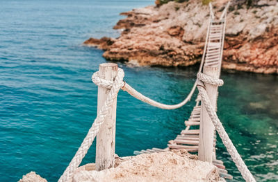 Old wooden rope bridge. foot bridge over water, sea, summer.