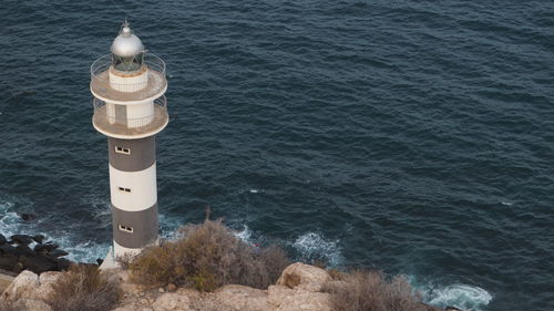 High angle view of lighthouse by sea against buildings