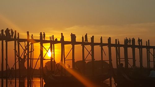 Silhouette pier over sea against sky during sunset