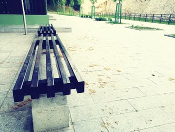 High angle view of empty bench on footpath