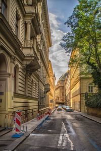 Road amidst buildings in city against sky