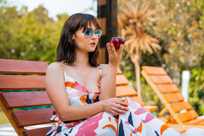 Full length portrait of young woman sitting outdoors