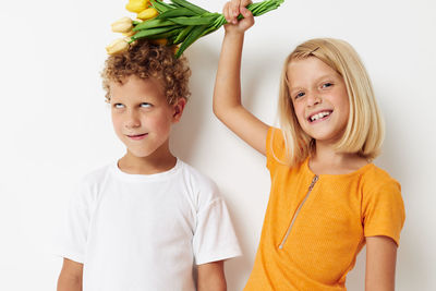 Portrait of girl holding bouquet on brothers head