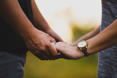 Close-up of a couple holding hands with an engagement ring 