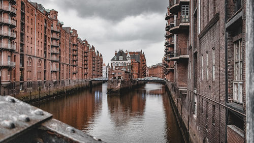 Bridge over canal amidst buildings against sky in city