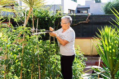 Young woman standing against plants