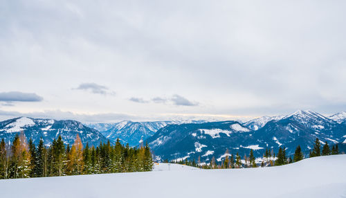 Scenic view of snowcapped mountains against cloudy sky