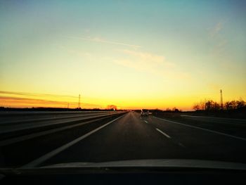 Cars on road against sky during sunset