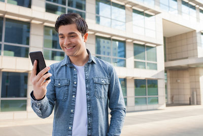 Young man using mobile phone while standing outdoors