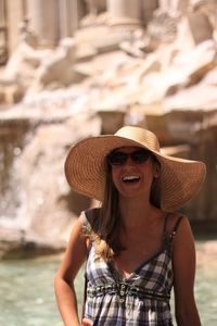 Cheerful young woman wearing hat and sunglasses at beach