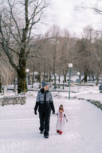 Rear view of woman walking on snow covered field