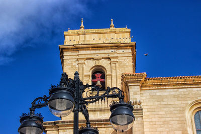 Low angle view of lights and church against blue sky