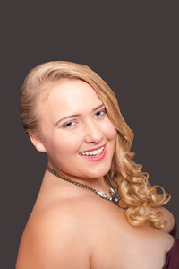 Portrait of smiling young woman against gray background