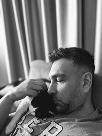 Close-up of man sleeping with cat on sofa at home