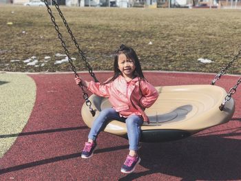 Portrait of happy girl sitting on slide at playground
