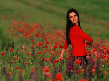 Portrait of smiling young woman by poppy field