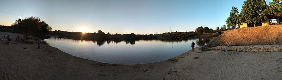 Scenic view of lake against clear sky at sunset