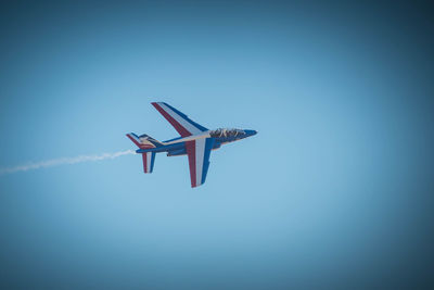 Low angle view of airplane flying against clear blue sky