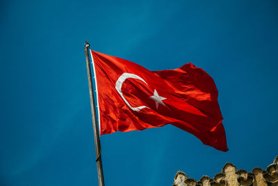 Low angle view of flag against blue sky