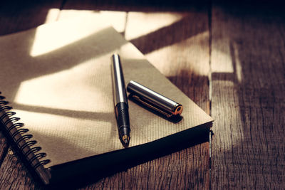 High angle view of pen and spiral notebook on wooden table