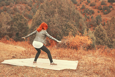 Full length of woman with arms raised on field