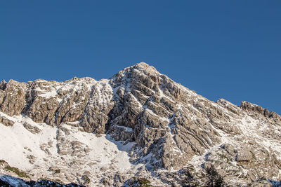 Low angle view of snowcapped mountain against blue sky