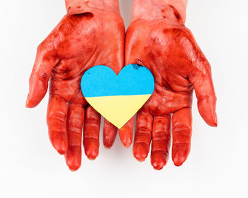 Bloody female hands with the flag of ukraine in the shape of a heart on a white background. 