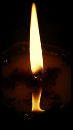 Close-up of lit candle over black background