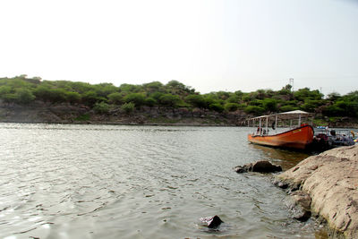 Boat moored in river against clear sky