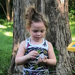 Cute girl standing by tree trunk