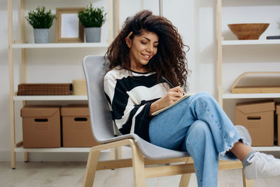 Portrait of young woman sitting on chair at home