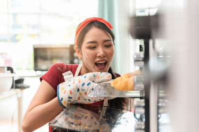 Smiling baker preparing bun at oven