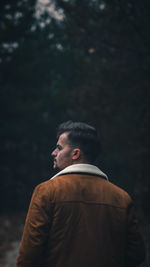 Rear view of man standing against trees