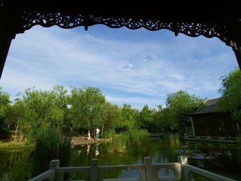 Scenic view of lake by trees and building against sky