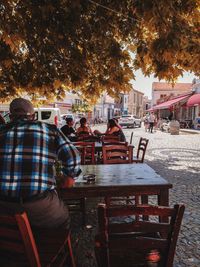 Rear view of people sitting on table during autumn