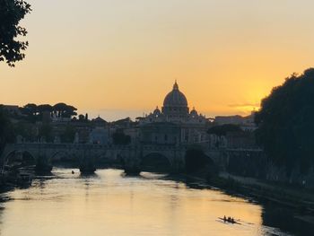 River amidst buildings against sky during sunset